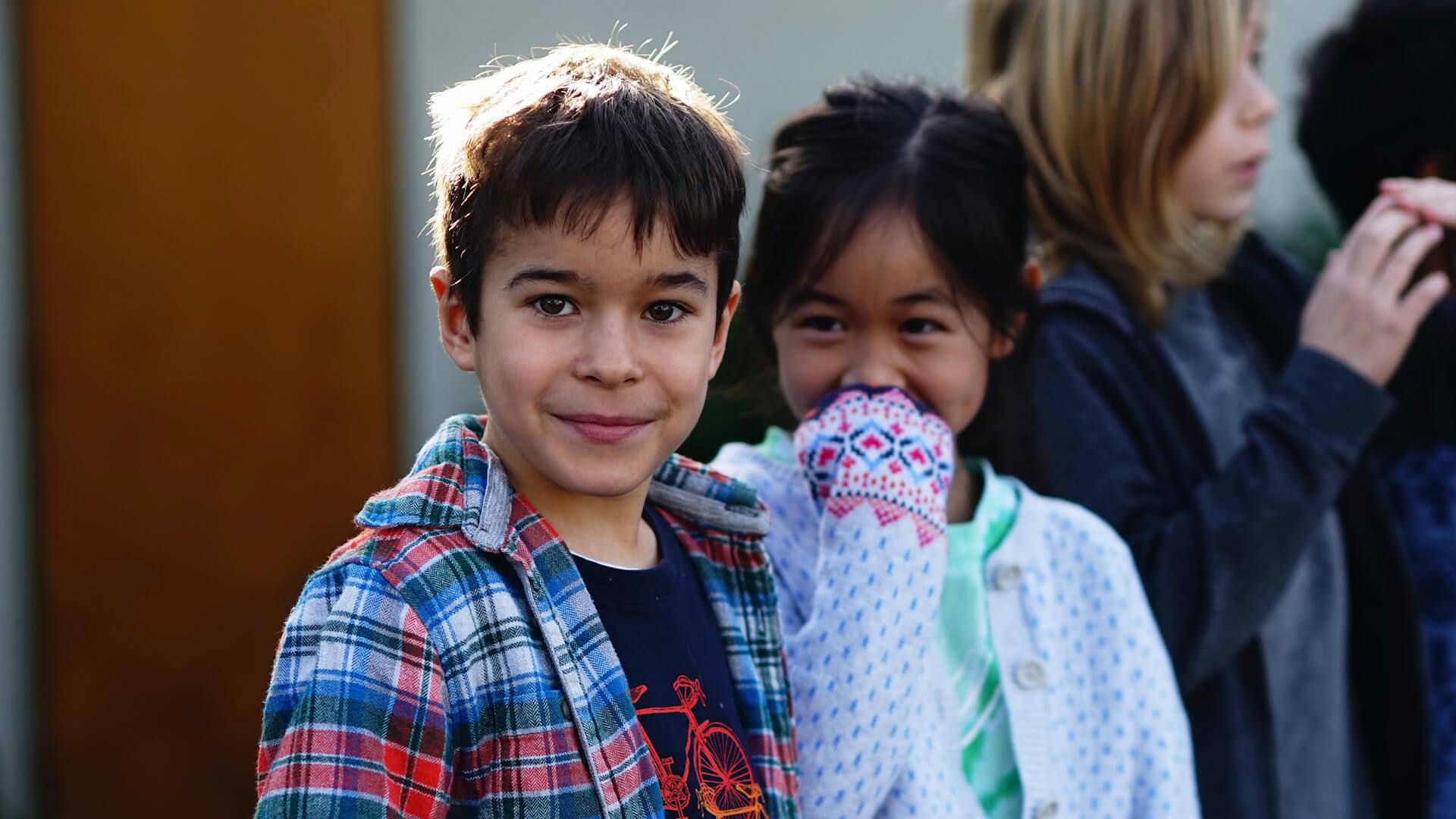 Lower school male and female students stand in line.