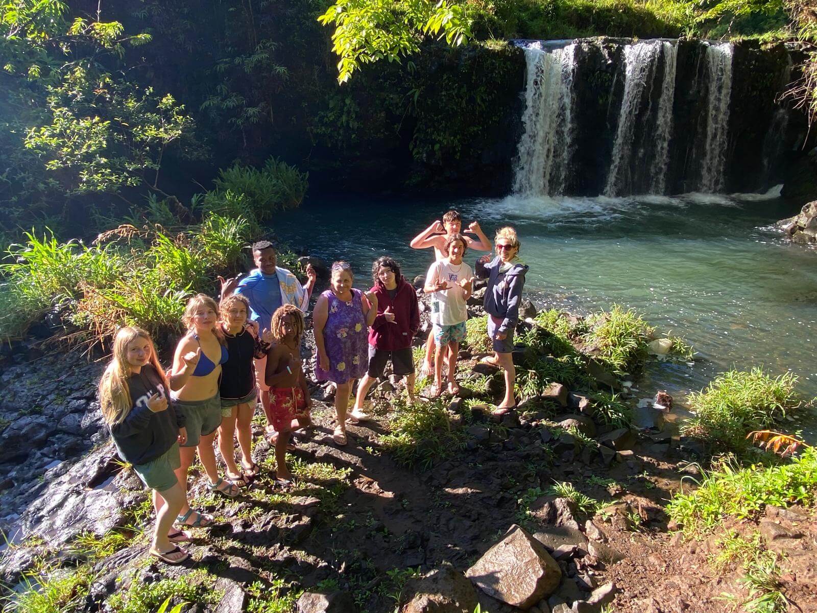 Middle School students and teacher on Hawaii field trip at a waterfall.