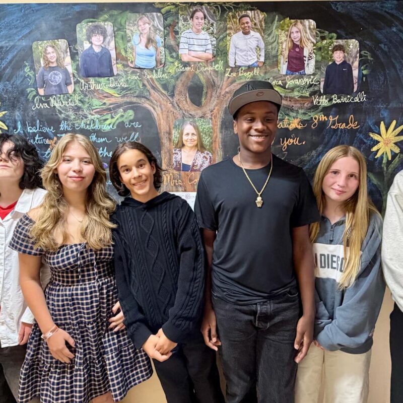 Students stand against a wall of art.