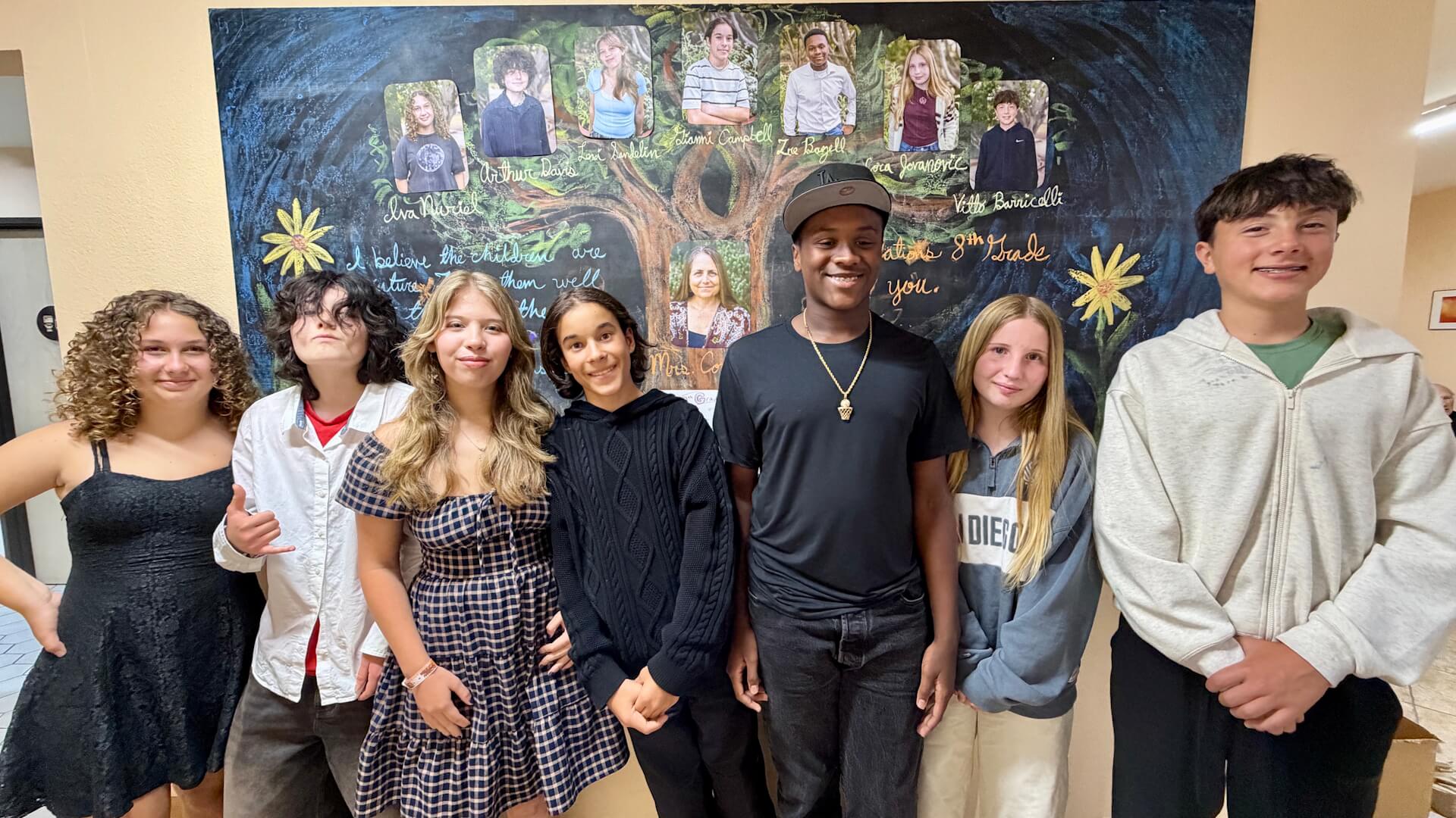 Students stand against a wall of art.