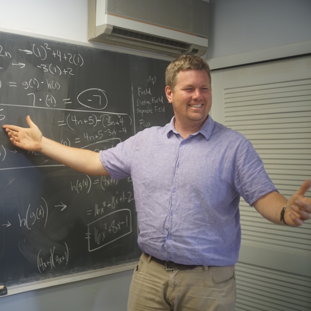 Male teacher at chalkboard.