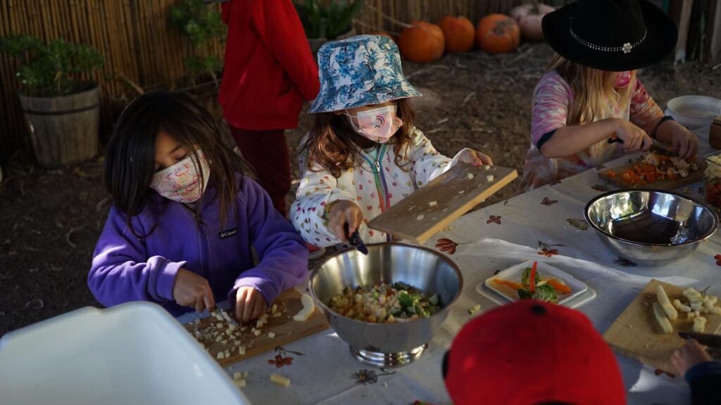 Lower School female students chop vegetables for Soup Day