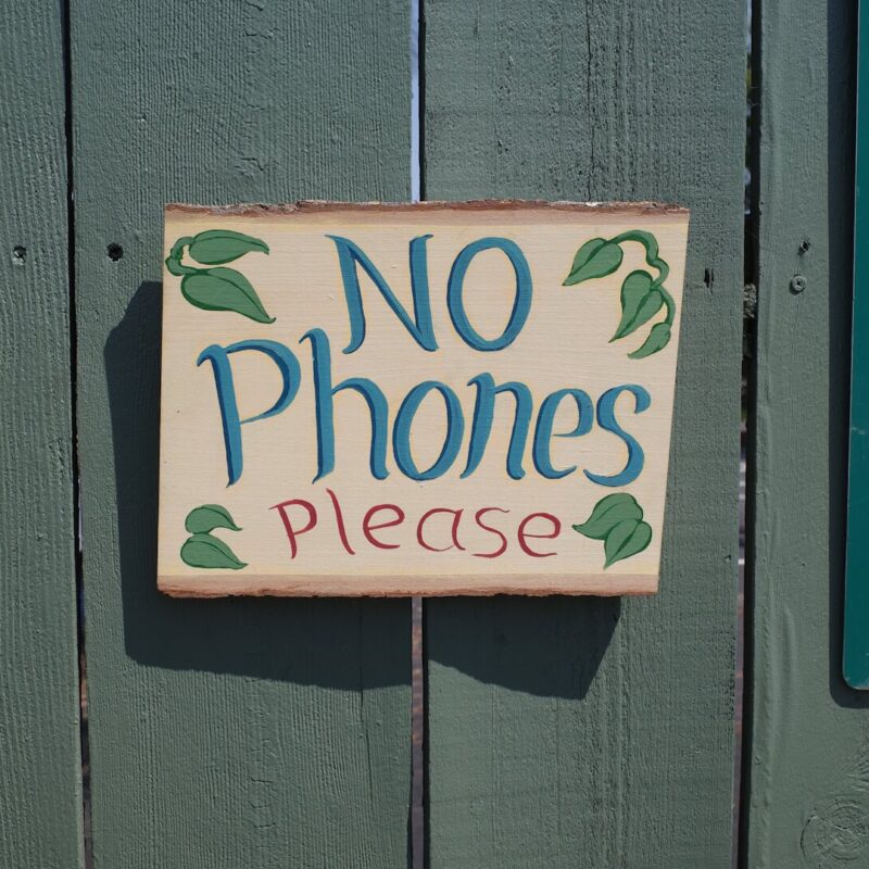 No phones please sign hanging on fence